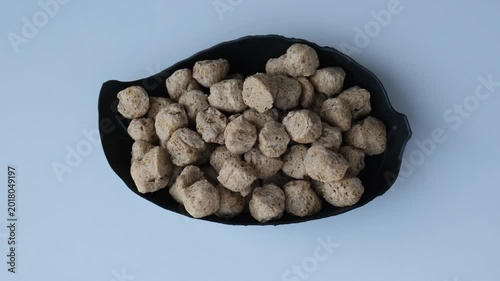 Top view of dry soya chunks in a black leaf-shaped bowl on a white background