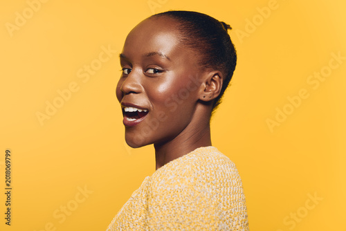 Foto Smiling African woman with dark skin wears yellow sweater against bright yellow background