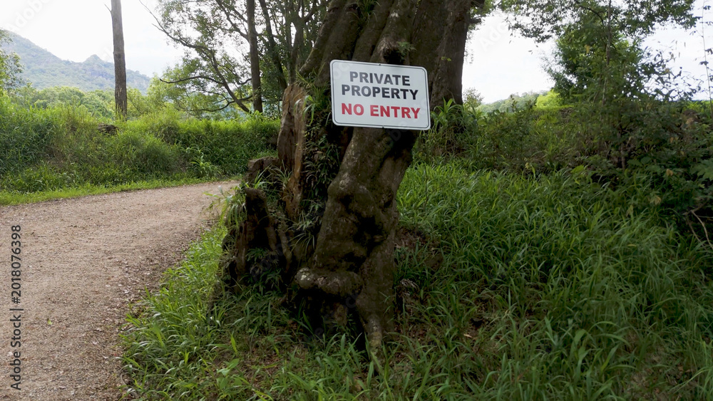 Naklejka premium Private Property No Entry Sign Posted on Tree Along Rural Path