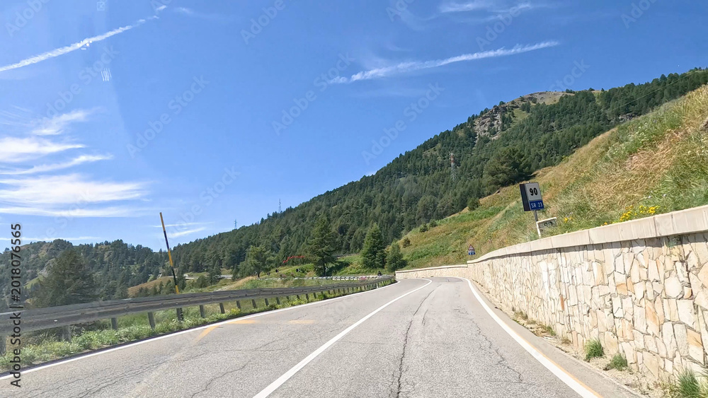 Obraz premium Winding Mountain Road with Stone Wall in Piedmont Italy Under Blue Sky