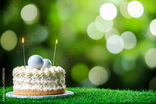 Minimal golf themed birthday cake with golf balls and candles on green grass background featuring soft bokeh and large copy space for celebration designs.
