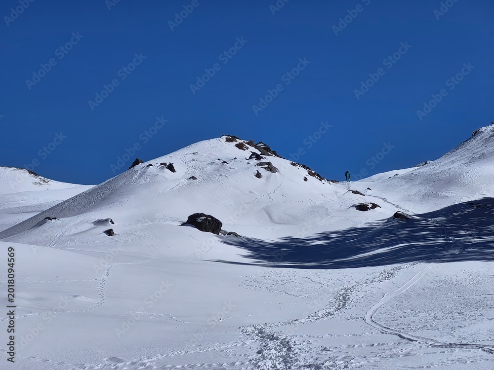 Fototapeta premium Snowy winter landscape with trekking trails and tiny hikers at Gorson Bugyal, Uttarakhand