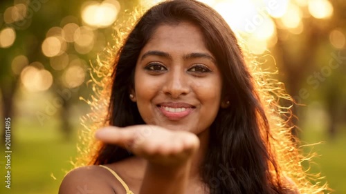 Beautiful young Indian woman blowing flying kiss to the camera during golden hour