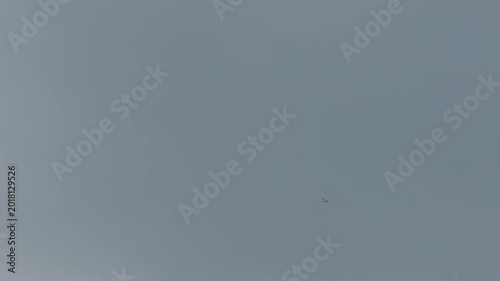 Distant Airplane Flying Against a Grey Overcast Sky