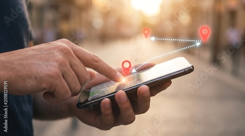 Close up view of person using smartphone to navigate city streets with digital map overlay showing red location pins and directional path indicators for urban travel and logistics planning