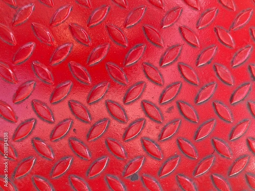 A weathered red steel staircase surface covered with repeating oval patterns, marked by age and dark stains formed through years of use.