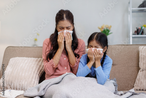 Mother and daughter experiencing cold flu symptoms at home