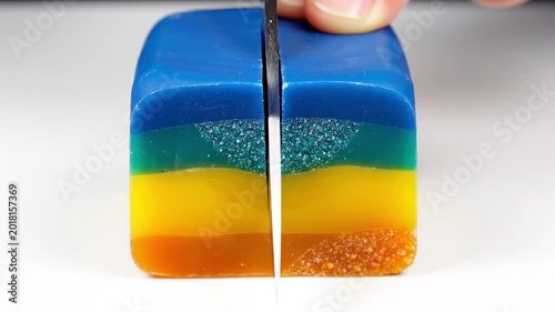 Woman slicing a block of multilayered colorful kinetic sand soap. Creative hobby for stress relief. Artistic craft activity with texture and vibrant color layers.
