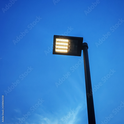 Modern LED street lamp against blue sky. Concept of urban infrastructure, public outdoor lighting, and smart city development.