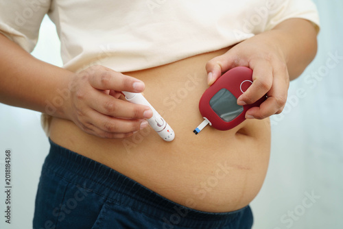 Asian woman injecting herself diabetes injecting insulin in stomach at home.
