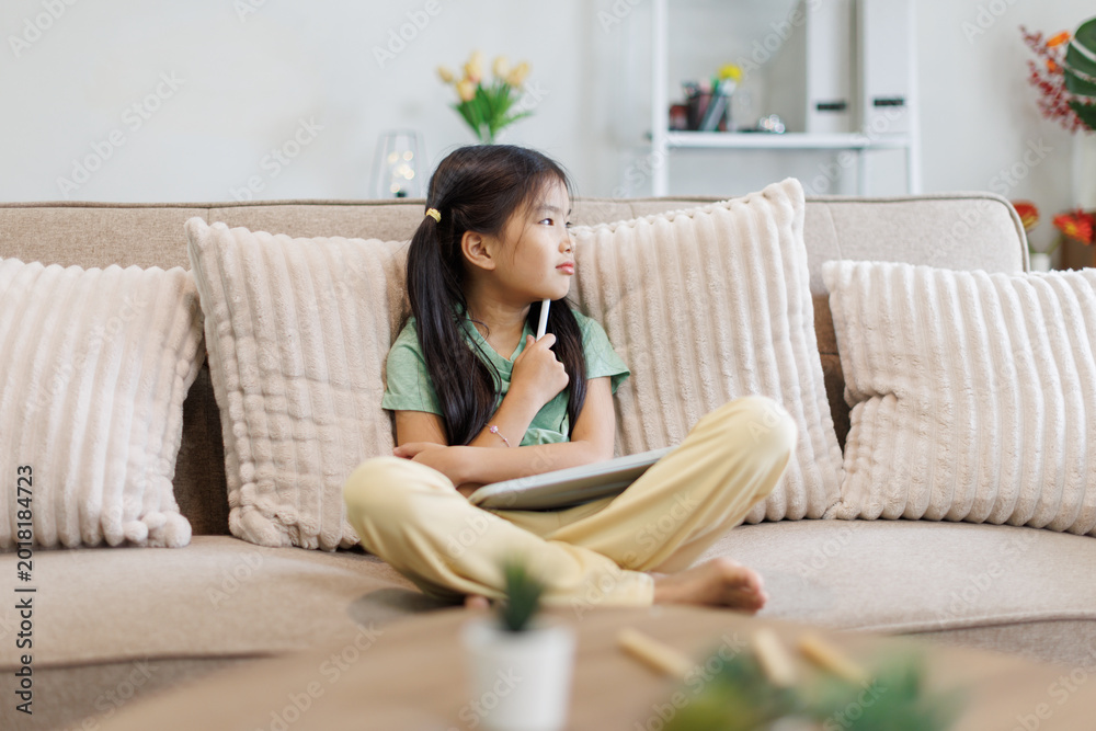Obraz premium Young girl thinking during online learning at home