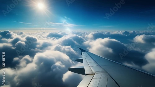 Airplane wing above a sea of clouds at sunrise with sun and blue sky