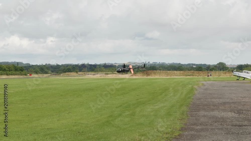 Black Robinson R44 Raven II helicopter hovering low to the ground stock footage