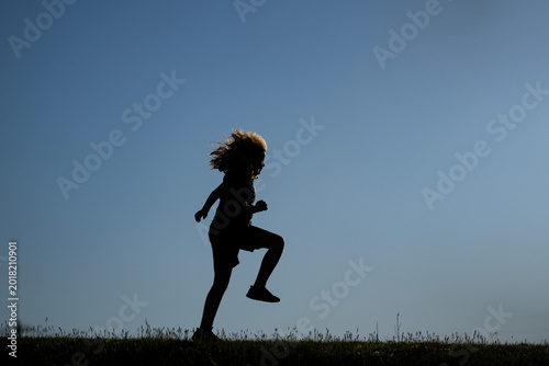 Fotografie Kid silhouette jumps in sunlight