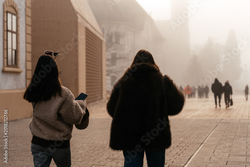 Foto Two people walking along a misty Liechtenstein European city street in soft morning light