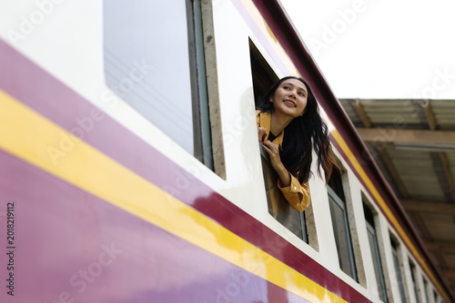 Canvas Print Young woman enjoying train journey looking out window while enjoying the scenic view during her travel