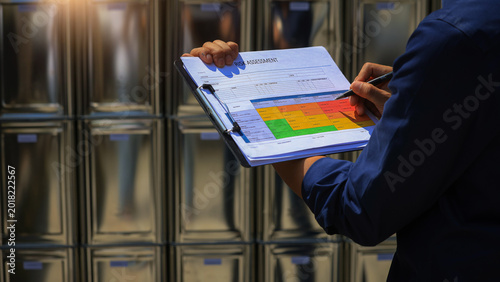 Fotografi Focused warehouse worker holding clipboard with safety chart doing important haz