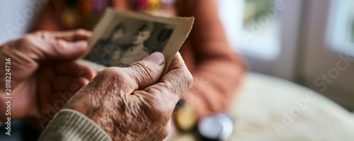 Elderly veterans comparing faded military photographs during reunion  