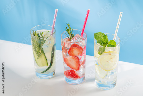 Set of fresh non alcoholic drinks with strawberry cucumber and lemon on blue background
