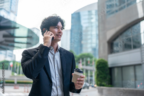 Asian young businessman talking on mobile phone while spend time in city. 