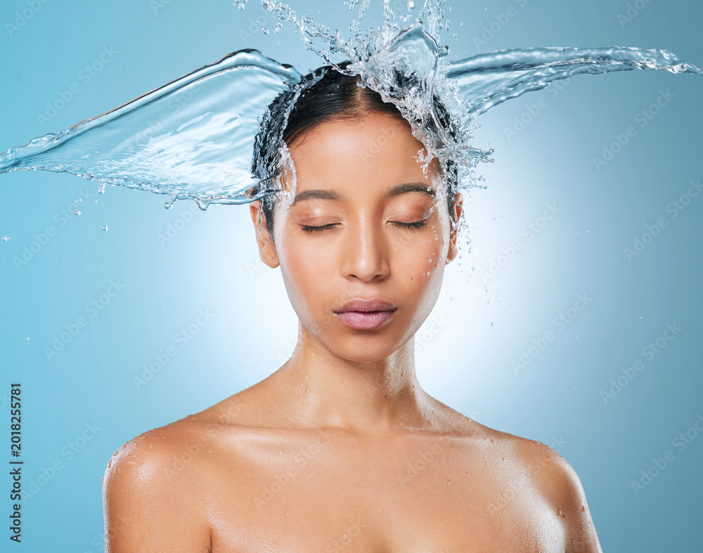Naklejka premium Water, hair and splash with woman in studio for beauty, hydration cosmetics and cleaning. Self care, liquid and moisture with female person on blue background for shower, washing and shampoo