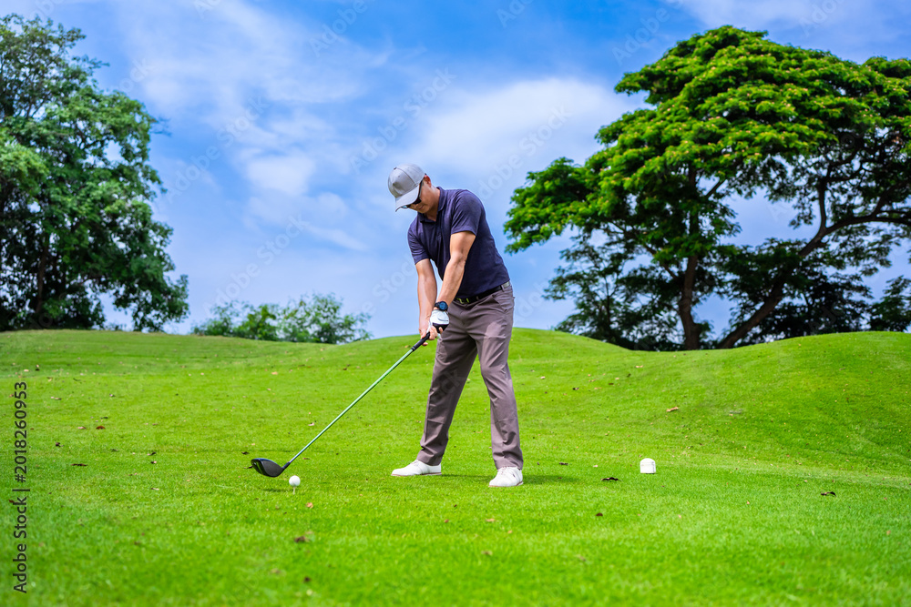 Fototapeta premium Professional young male golfer swings his club on scenic golf course