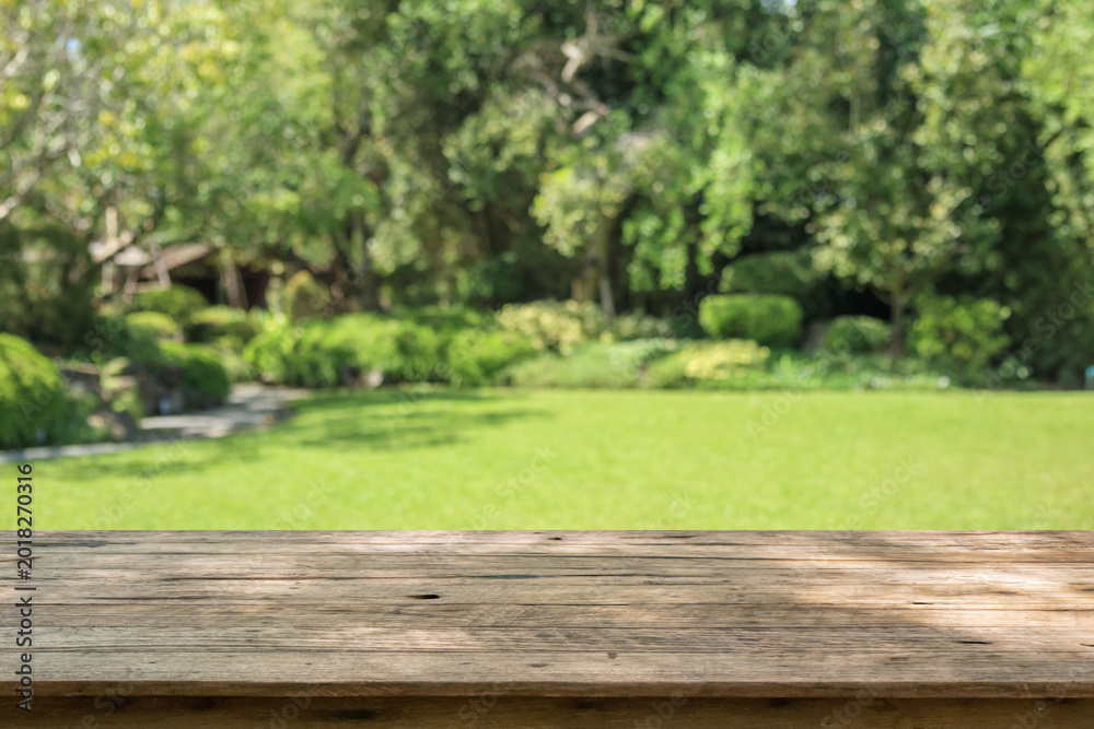 Obraz premium Empty wood table top with abstract blur park garden background