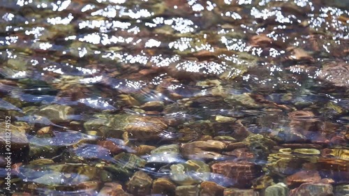 High angle shot of fast flowing river water creating shimmering abstract light patterns and bokeh.