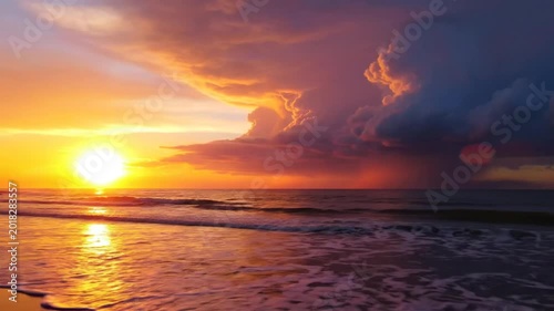 Stunning golden sunset over the ocean with dark storm clouds on the horizon reflecting on the wet beach