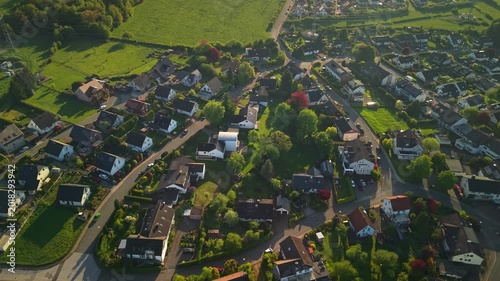 Aerial panorama of German countryside village with residential houses and green farmland at golden hour