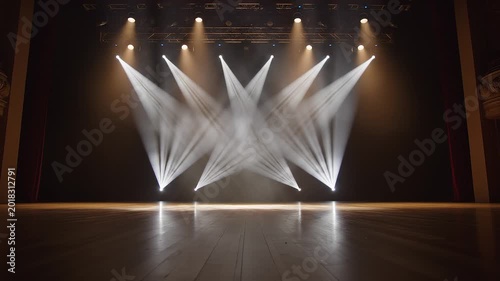 Empty performance stage with rustic wooden floorboards illuminated by moving white spotlights and smoke effects.