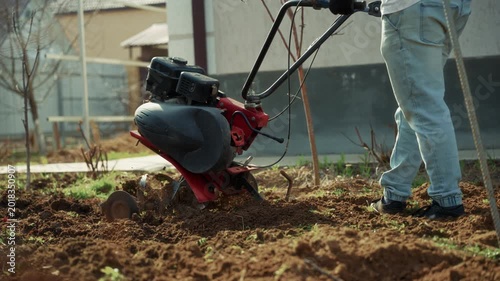 Man preparing garden soil with motor cultivator