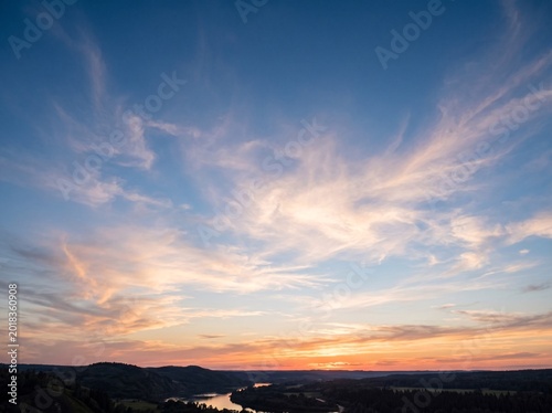 Aerial view of a winding river at sunset with clouds