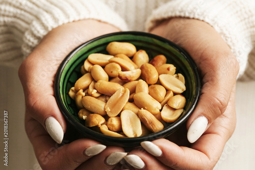 Cuadro en lienzo Woman holding bowl with peanuts close up