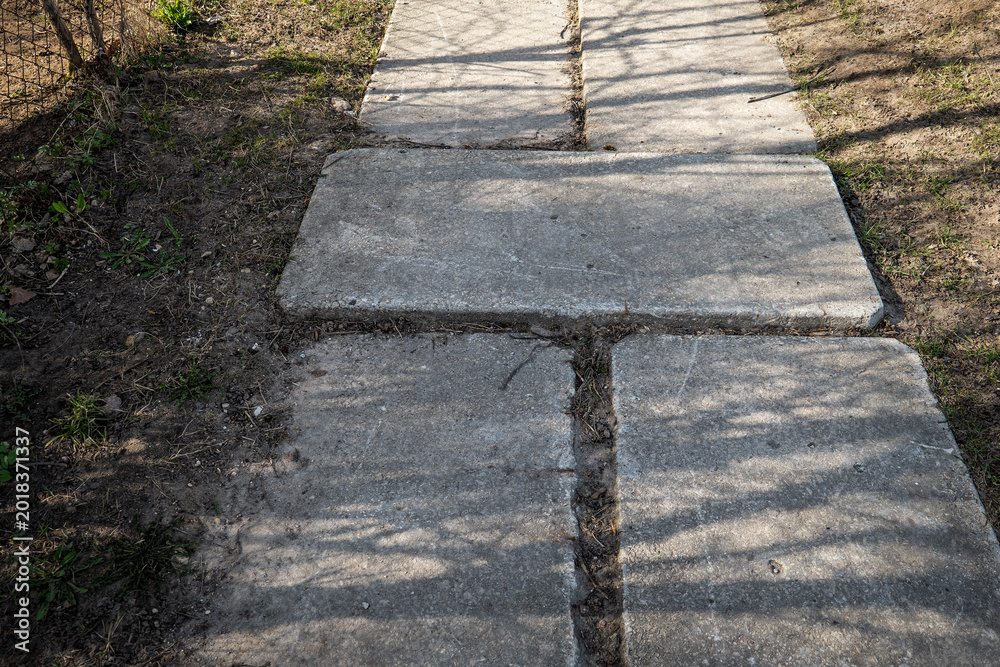 Fototapeta premium Damaged Concrete Sidewalk Slabs With Uneven Surface in Residential Area