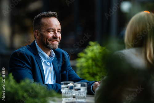 Smiling man having business conversation at outdoor cafe
