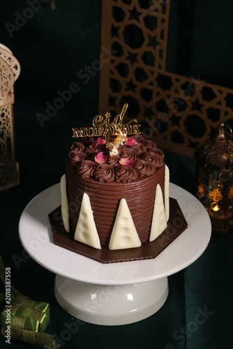 Chocolate cake (sponge, mousse, crunch, sauce) arranged artistically and separated on the plate, with Eid Mubarak topper.