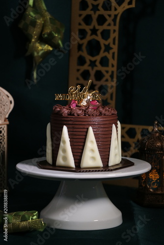 Chocolate cake (sponge, mousse, crunch, sauce) arranged artistically and separated on the plate, with Eid Mubarak topper.