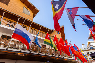International flags waving on wooden building facade against blue sky