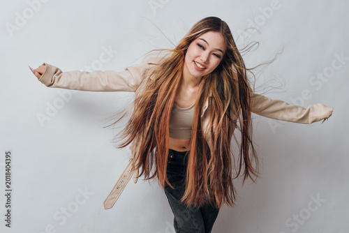 Foto Young woman with long hair and dreadlocks posing with arms outstretched smiling and wearing casual clothes on plain light background in studio photo session