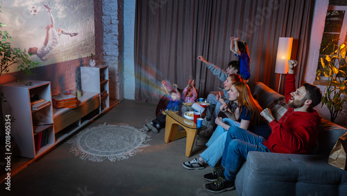 Fotografie Happy family watching soccer projection at home during football fan night