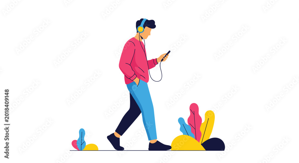 Fototapeta premium Young man walking while listening to music through headphones and looking at his smartphone on a clean white background.