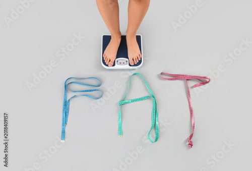Cuadro en lienzo Woman's feet measuring weight and word FAT made of tapes on light background, top view