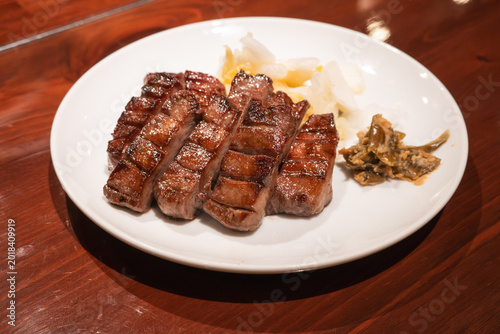 Tableau sur toile Thick cut grilled beef tongue served with pickled cabbage on white plate