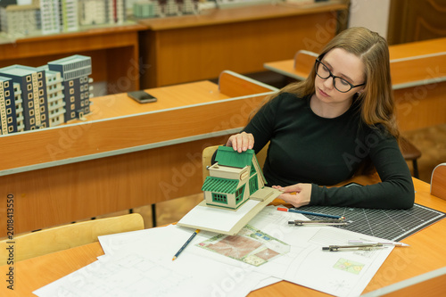 Caucasian young woman making a model of a building. Student of the construction university. 