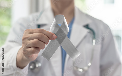 Silver color ribbon awareness on doctor's hand support, symbolic bow color for Parkinson's disease, Brain cancer, Schizophrenia, Sciatic Pain and Brain disorder or disability illness