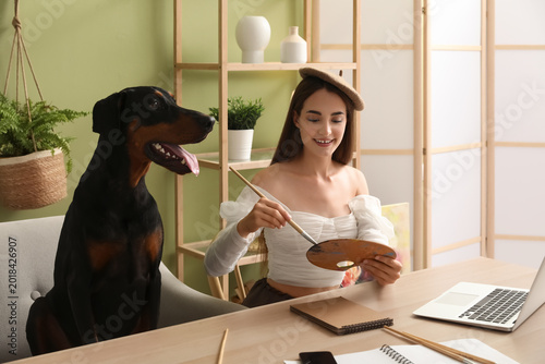 Schilderij op canvas Cute Doberman dog and beautiful young happy woman in beret with laptop holding p