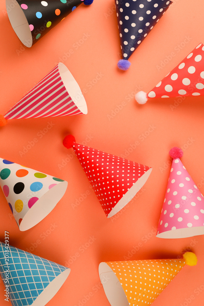 Obraz premium Colorful birthday caps on orange background. Top view.