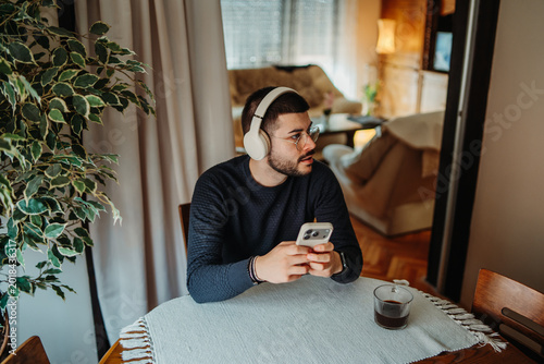 Man relaxing at home listening to music on smartphone