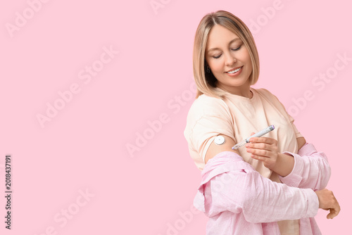 Bild auf Leinwand Woman with glucose sensor for measuring blood sugar level and lancet pen on pink background